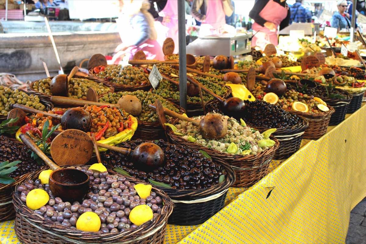 Olives et tapenades en vrac dans des paniers, sur un étal du marché